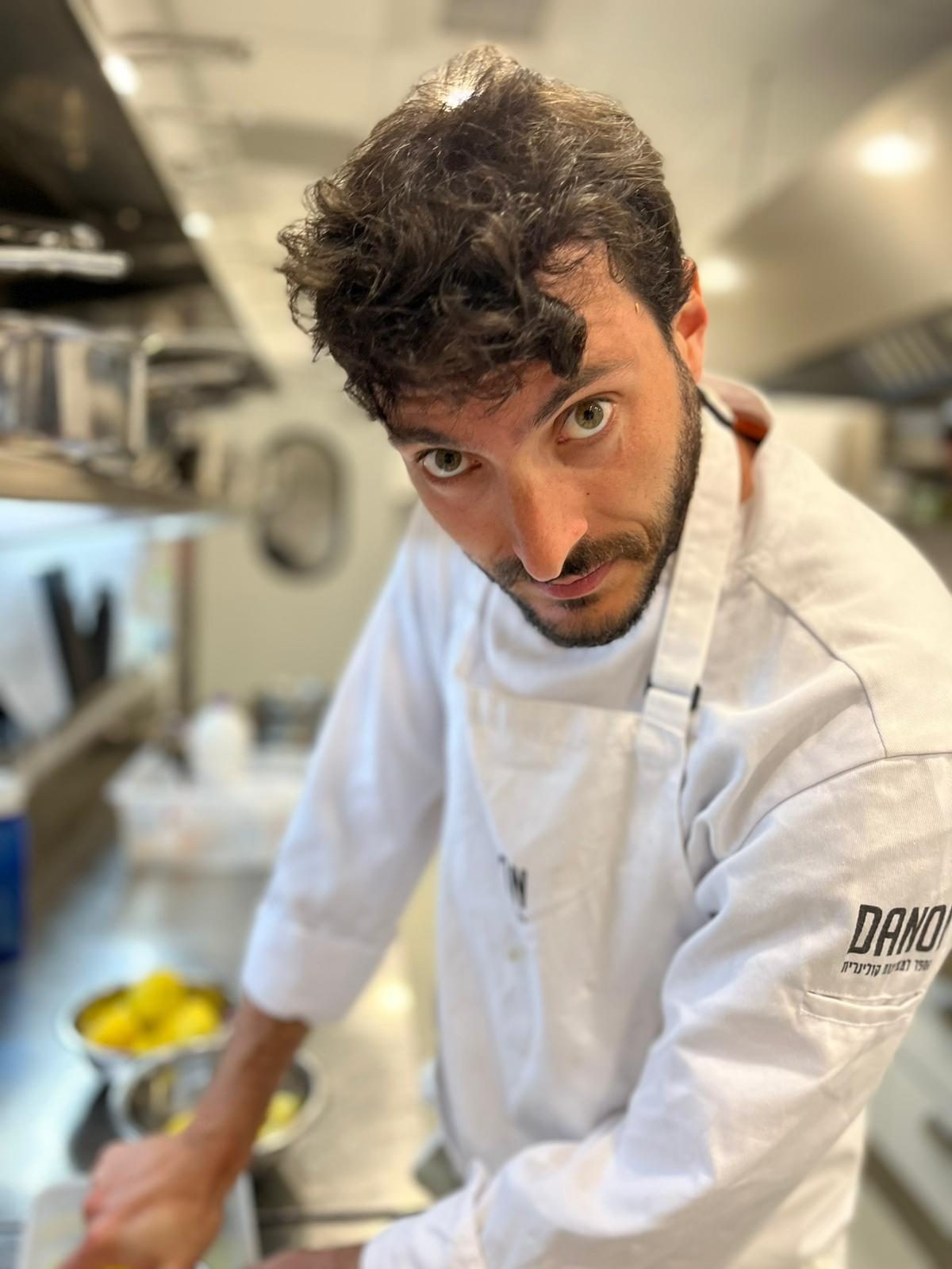 The chef at work in a professional kitchen, wearing Danon culinary school whites